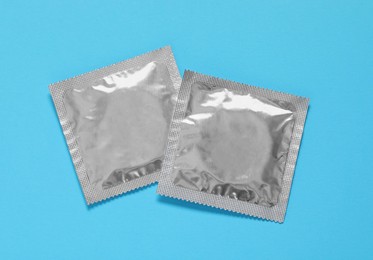 Photo of Condom packages on light blue background, flat lay. Safe sex