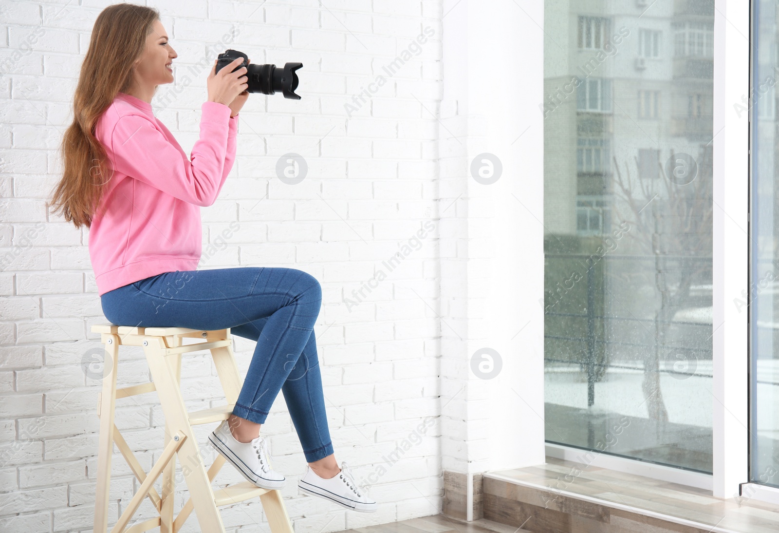 Photo of Female photographer with camera sitting on chair indoors