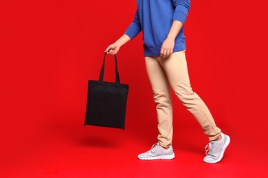 Photo of Young man with eco bag on red background, closeup