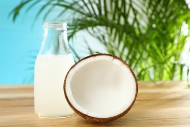 Composition with bottle of coconut water on wooden table against blue background