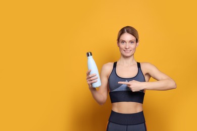 Photo of Sportswoman with thermo bottle on yellow background, space for text