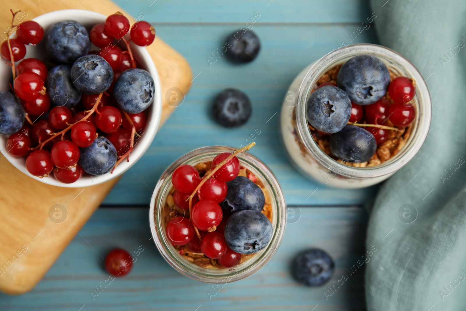 Photo of Delicious yogurt parfait with fresh berries on turquoise wooden table, flat lay