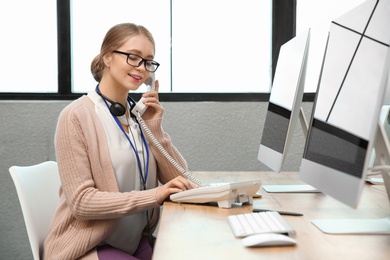 Photo of Technical support operator talking on telephone at table in office