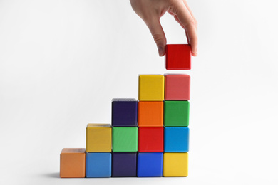 Photo of Woman building stairs with colorful cubes on white background, closeup. Career promotion concept