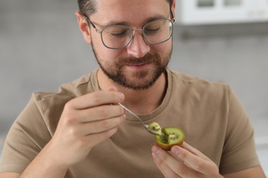 Man eating kiwi with spoon in kitchen