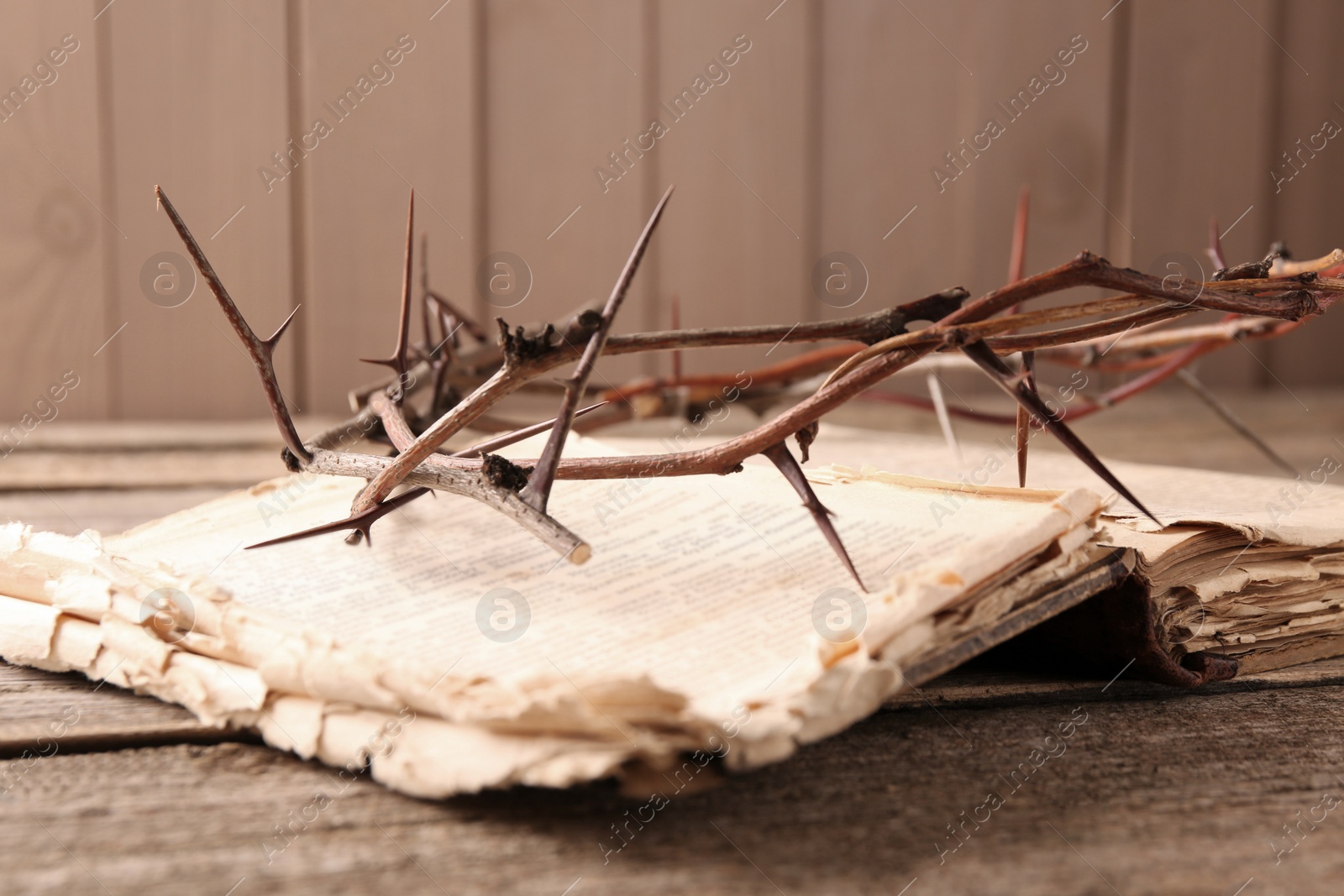 Photo of Crown of thorns and Bible on wooden table, closeup