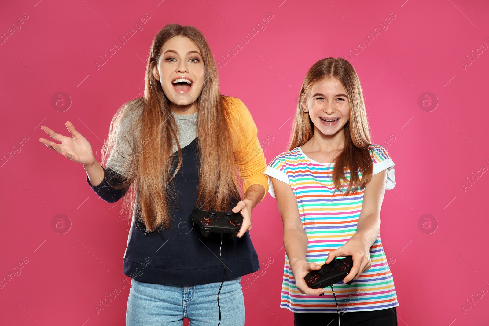 Photo of Young woman and teenage girl playing video games with controllers on color background