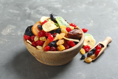 Photo of Bowl and scoop with different dried fruits on grey background. Healthy lifestyle