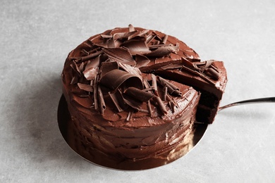 Photo of Tasty homemade chocolate cake and shovel with piece on table