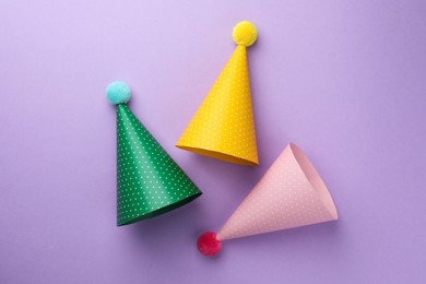 Beautiful party hats on purple background, top view