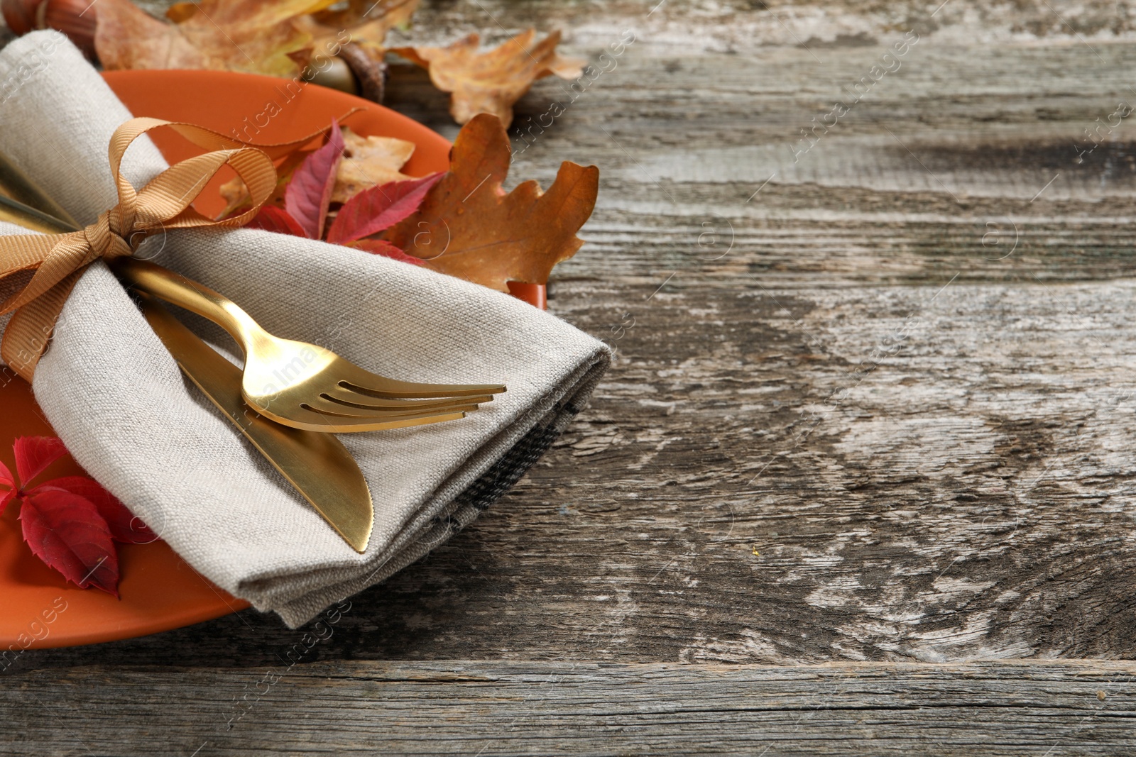 Photo of Festive table setting with autumn leaves on wooden background, closeup. Space for text