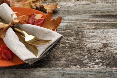 Festive table setting with autumn leaves on wooden background, closeup. Space for text