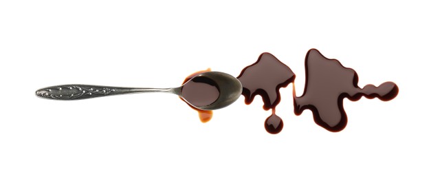 Photo of Spilled soy sauce and spoon on white background, top view