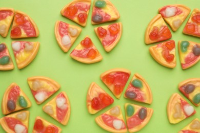 Tasty jelly candies in shape of pizza on green background, flat lay