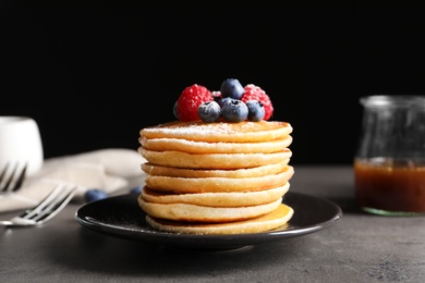 Photo of Tasty pancakes with berries and sugar powder on plate