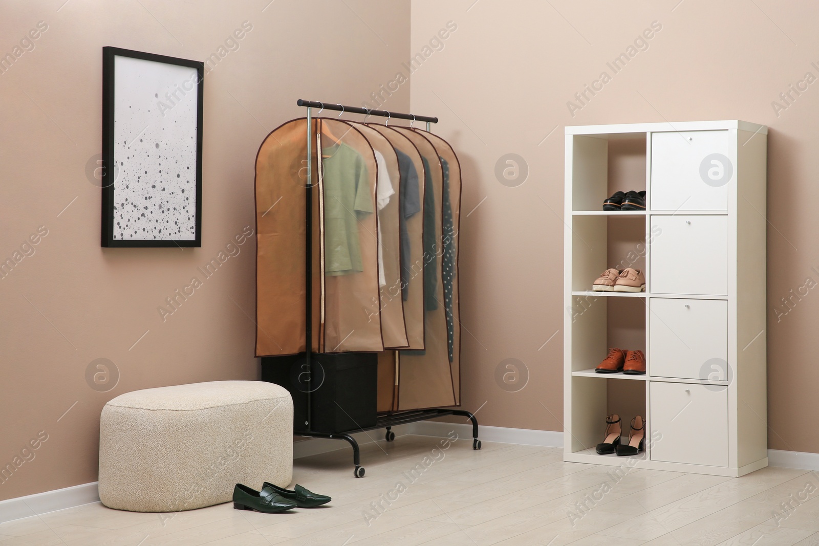 Photo of Garment bags with clothes hanging on rack in room