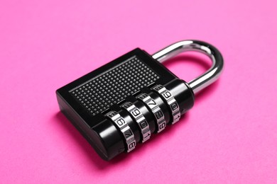 Photo of One steel combination padlock on pink background, closeup