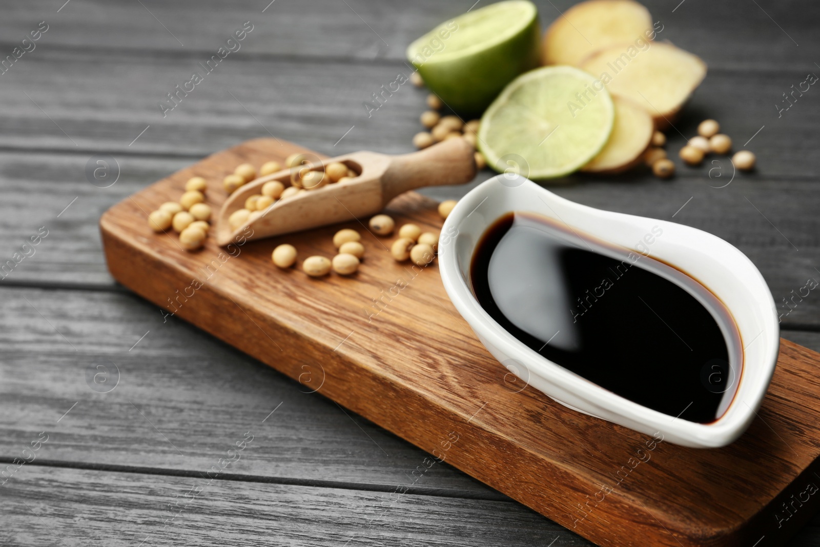 Photo of Board with dish of soy sauce and beans on table