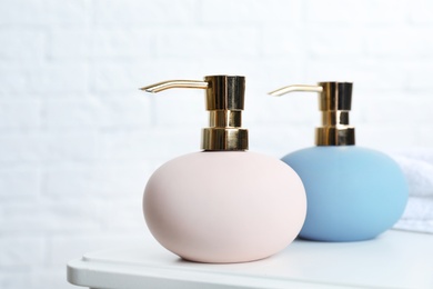 Stylish soap dispensers on table against blurred background. Space for text