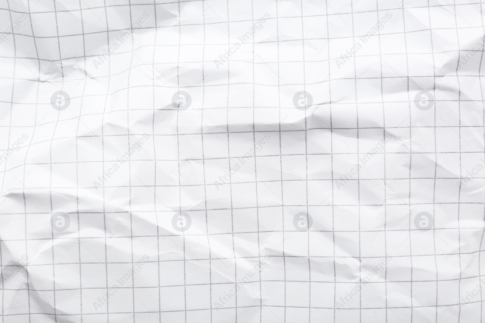 Photo of Crumpled checkered notebook sheet as background, top view