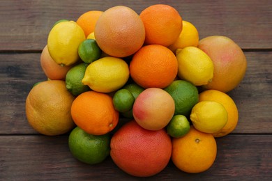 Photo of Different citrus fruits on wooden table, closeup