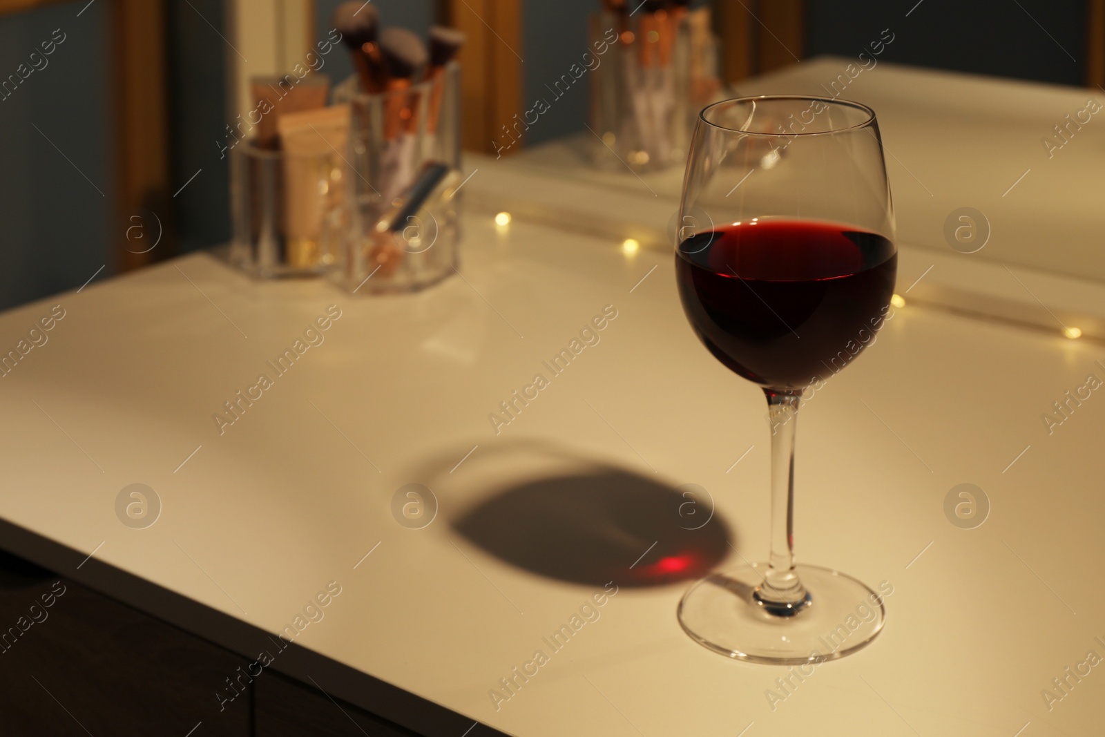 Photo of Glass of red wine on white table indoors, space for text
