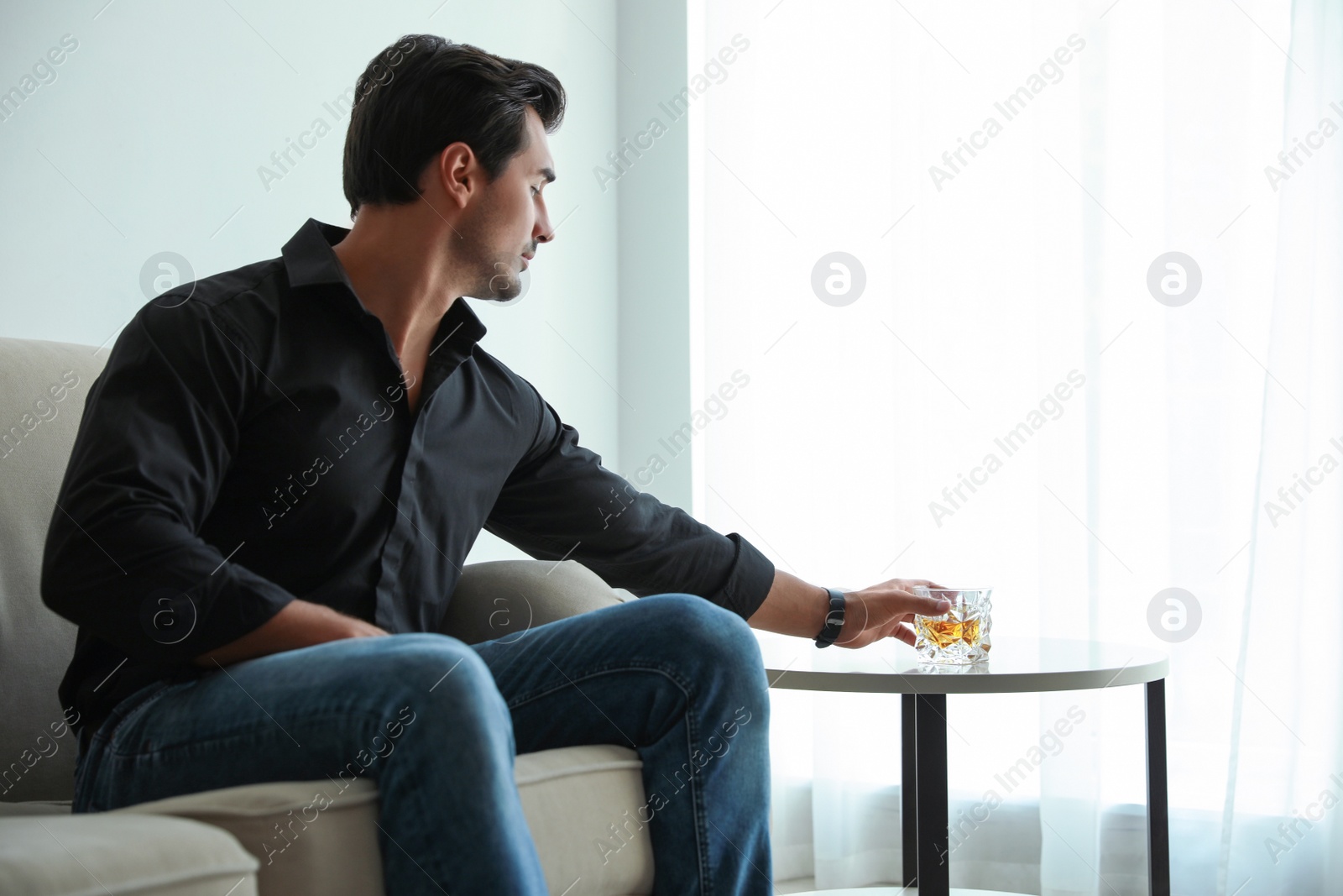 Photo of Young man with glass of whiskey at home