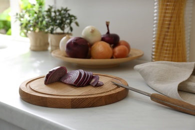 Photo of Red cut onion and knife on white countertop in kitchen