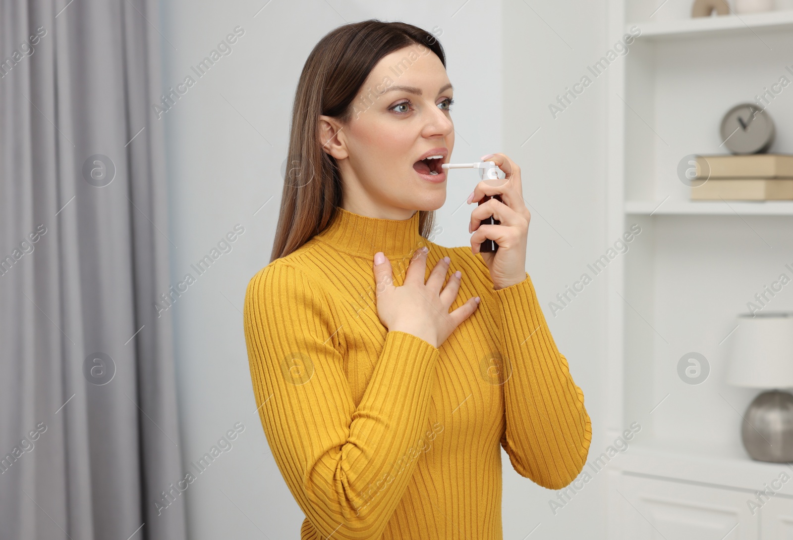 Photo of Adult woman using throat spray at home