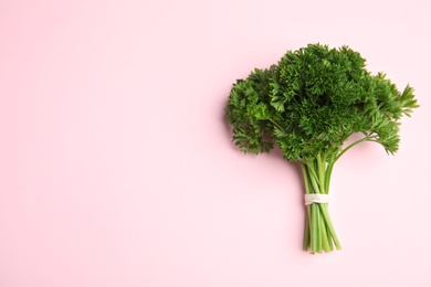 Photo of Bunch of fresh green parsley on pink background, top view. Space for text