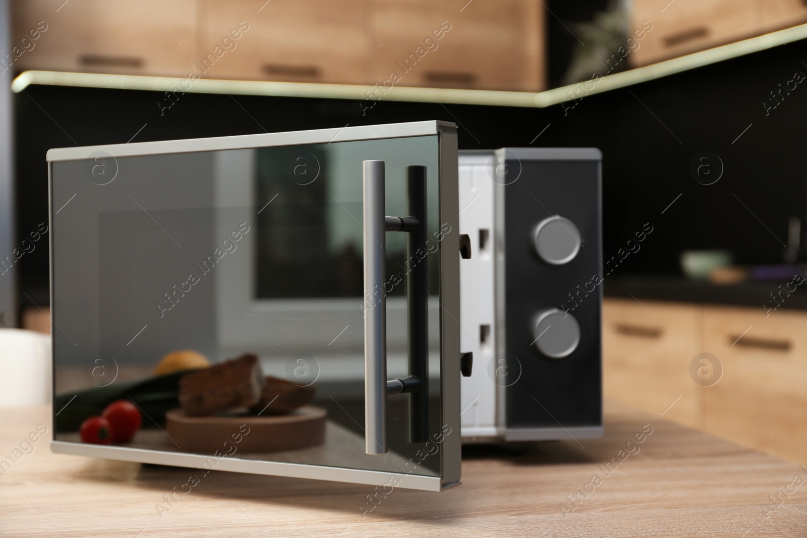 Photo of Open modern microwave oven on table in kitchen