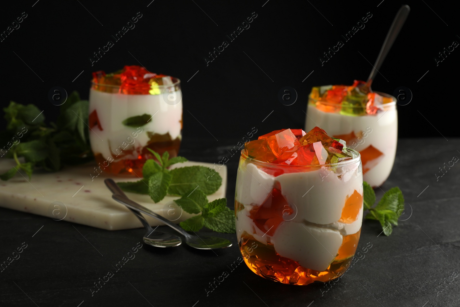 Photo of Delicious broken glass jelly dessert on black table, space for text