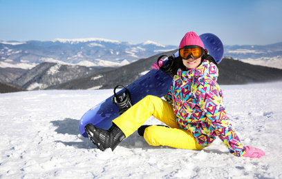 Photo of Young woman with snowboard on hill. Winter vacation