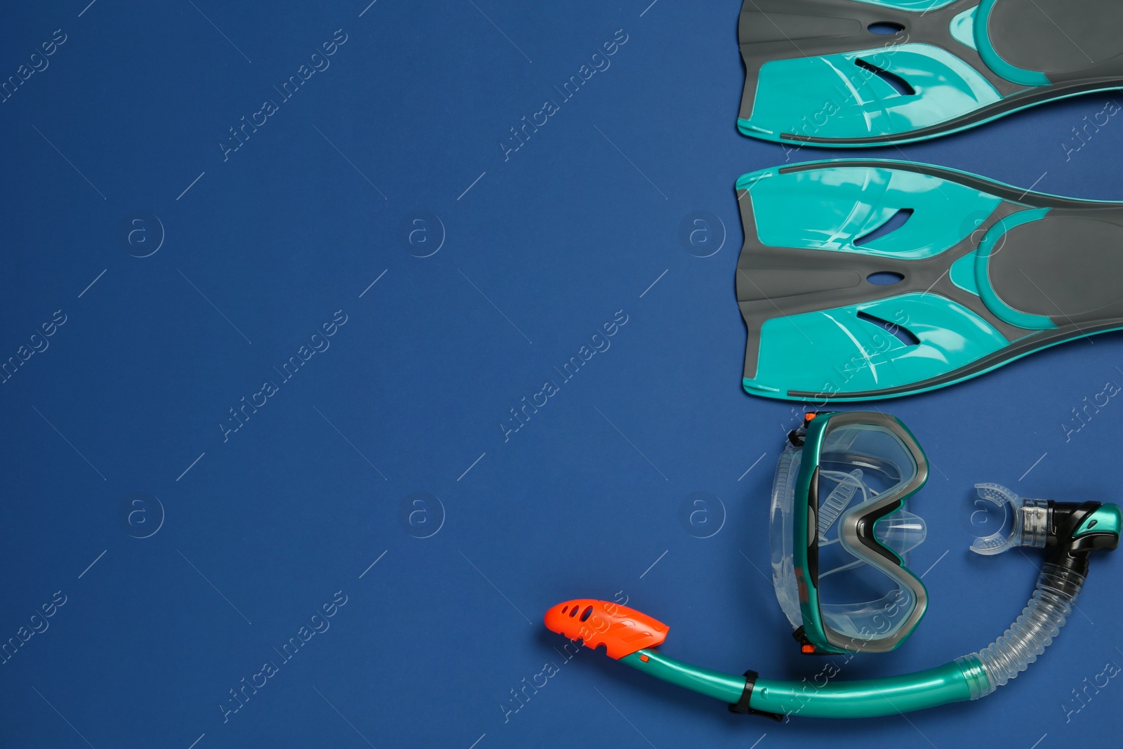 Photo of Pair of flippers, snorkel and diving mask on blue background, flat lay