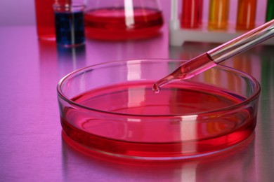Photo of Dripping red reagent into Petri dish with sample on table, closeup