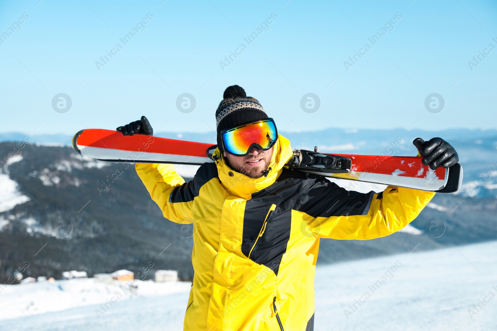 Photo of Happy man with ski equipment in mountains. Winter vacation