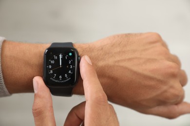 MYKOLAIV, UKRAINE - OCTOBER 04, 2019: Man using Apple Watch to check time on light background, closeup
