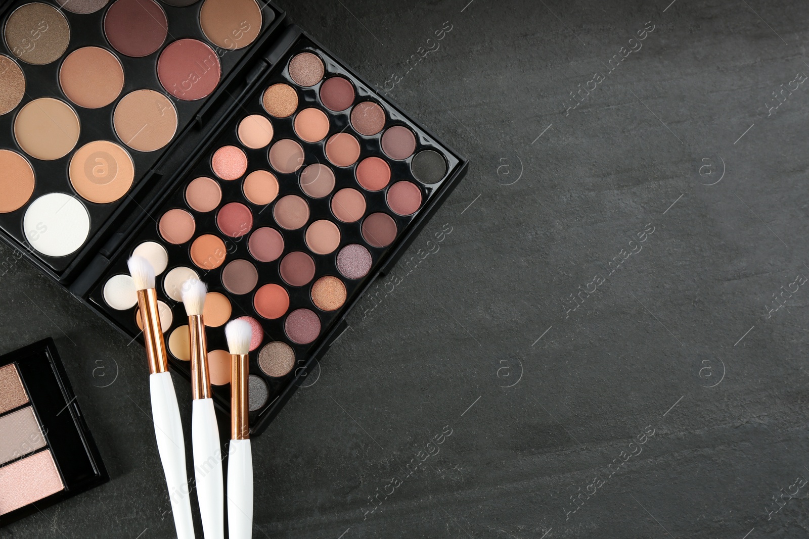 Photo of Flat lay composition with makeup brushes on black stone table, space for text