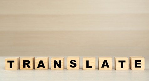 Photo of Word Translate made of wooden cubes with letters on table. Space for text