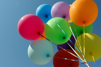 Photo of Bunch of colorful balloons against blue sky, bottom view