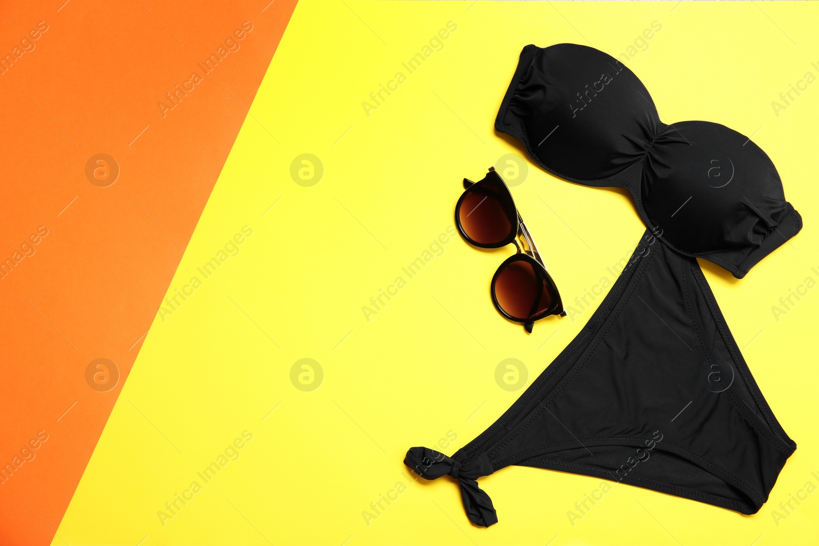 Photo of Stylish bikini, sunglasses and space for text on color background, flat lay