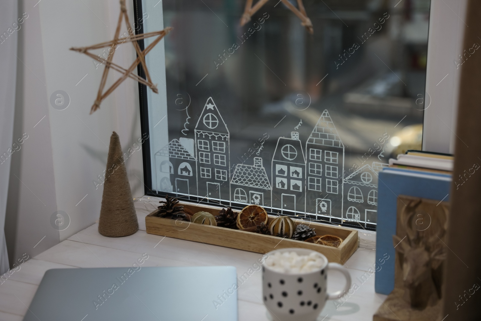 Photo of Laptop and hot drink on white wooden table near window with beautiful drawing at home. Christmas decor