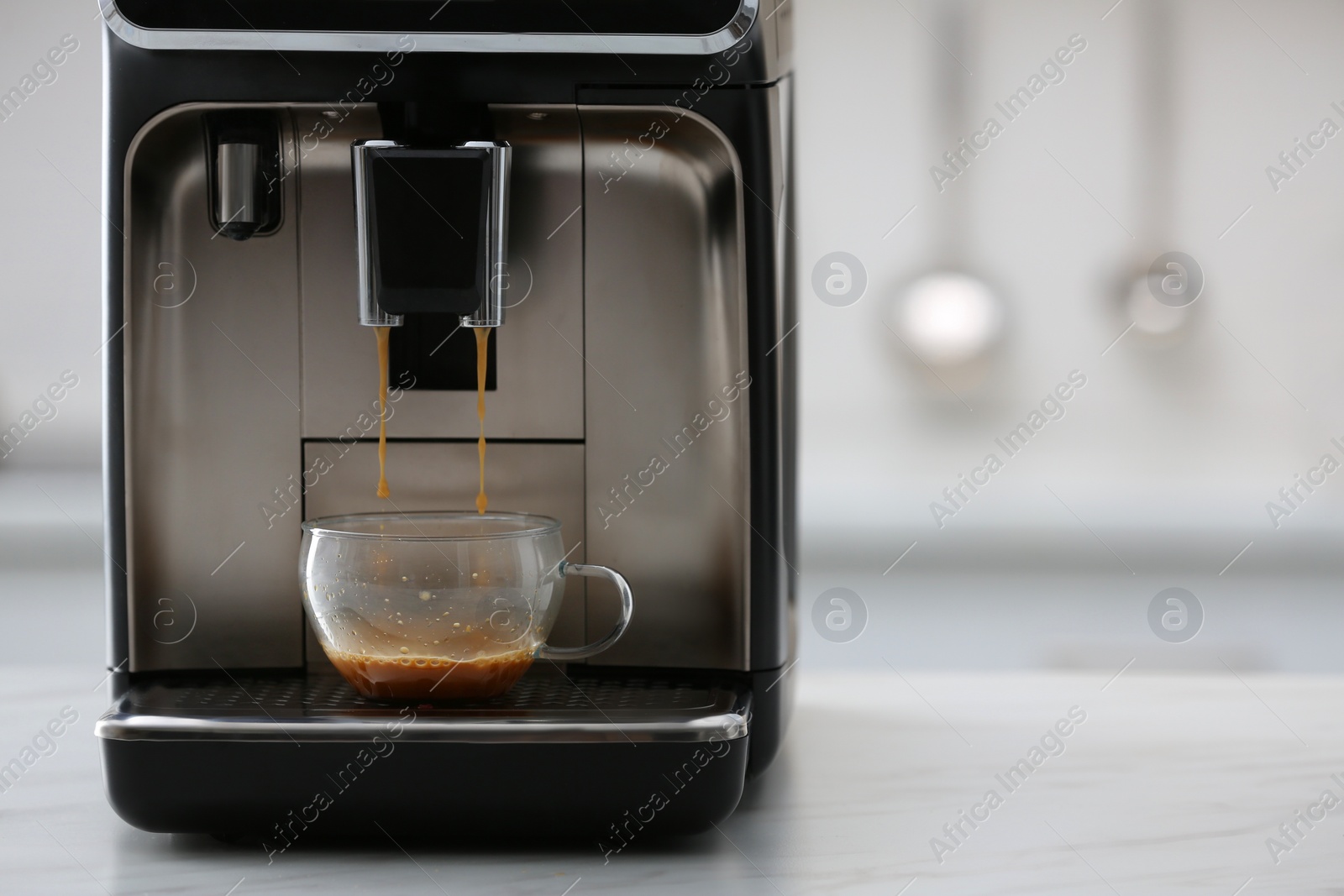 Photo of Modern electric espresso machine making coffee on white marble countertop in kitchen