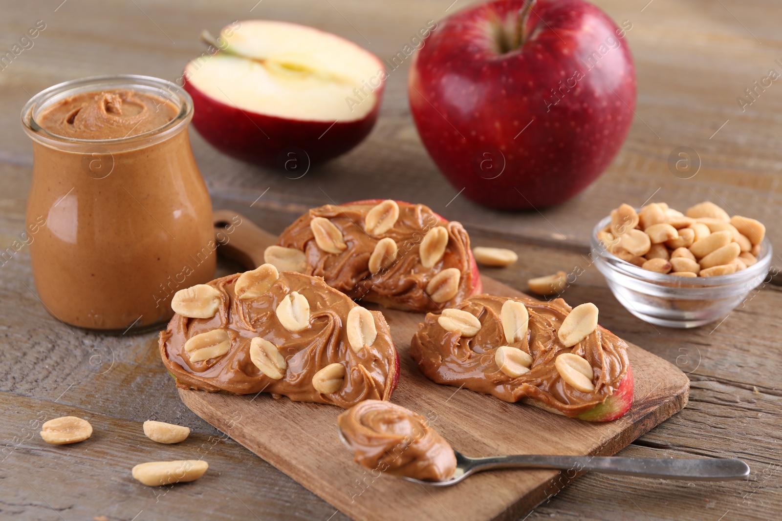 Photo of Slices of fresh apple with peanut butter and nuts on wooden table, closeup