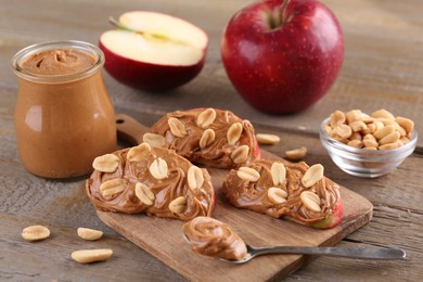 Slices of fresh apple with peanut butter and nuts on wooden table, closeup