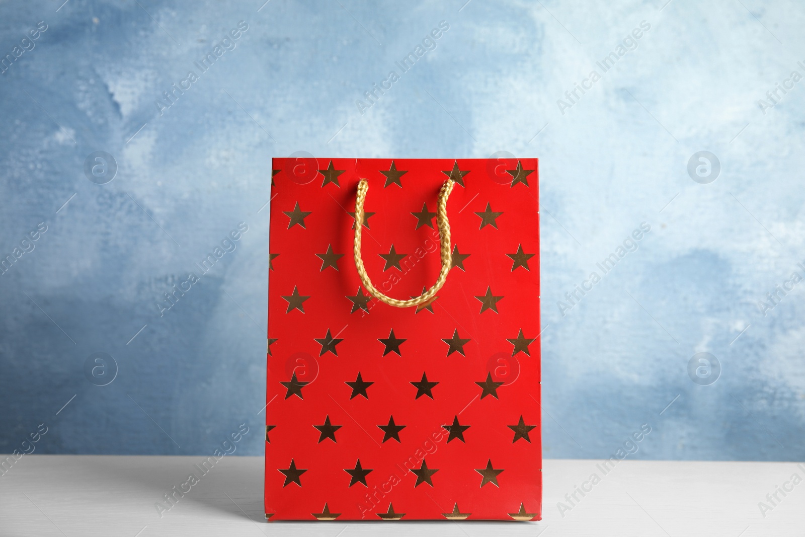 Photo of Red shopping paper bag with star pattern on white table