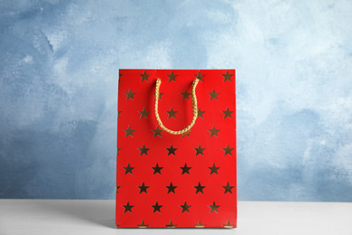 Photo of Red shopping paper bag with star pattern on white table