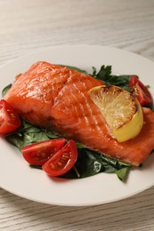 Photo of Tasty grilled salmon with tomatoes, lemon and basil on white wooden table, closeup