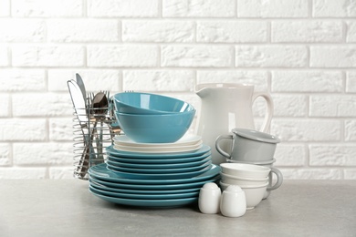 Photo of Set of clean dishes on table near brick wall