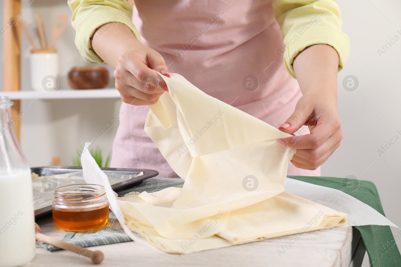 Photo of Making delicious baklava. Woman with dough at white table, closeup